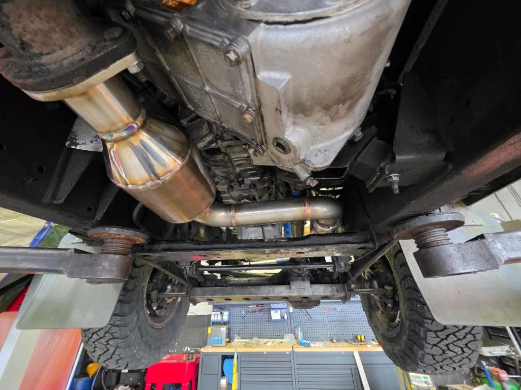 Gemonteerde RVS-downpipe onder Land Rover Defender op de brug