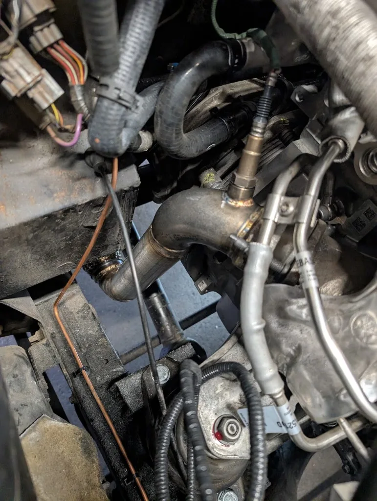 Downpipe met O2-sensorbus in de motorruimte van de Defender